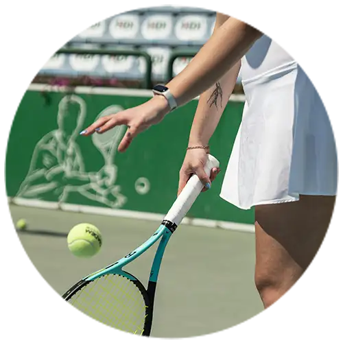 A tennis player wearing a smartwatch and bracelet prepares to serve on an outdoor court, holding a tennis racket and a ball, showcasing waterproof jewelry.