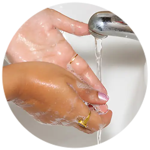 Close-up of hands washing under a faucet with soap, featuring gold rings on the fingers, emphasizing cleanliness and elegant jewelry.