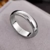 Polished silver ring with a smooth, shiny finish placed on a soft, neutral surface.