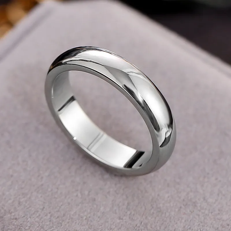 Polished silver ring with a smooth, shiny finish placed on a soft, neutral surface.