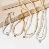A set of gold and silver-plated pearl necklaces and bracelets with crystal pendants, displayed on a textured surface, creating a chic and sophisticated look.