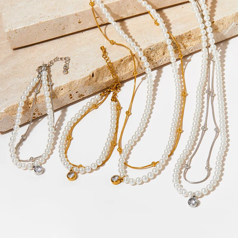 A set of gold and silver-plated pearl necklaces and bracelets with crystal pendants, displayed on a textured surface, creating a chic and sophisticated look.