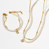 A matching 18K gold-plated pearl necklace and bracelet set with crystal pendants, displayed on a white background for a sophisticated presentation.