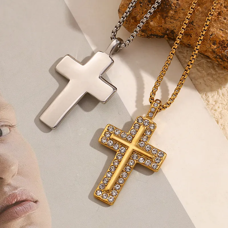 A silver and gold cross pendant, each with its own chain, with the gold cross decorated with cubic zirconia stones, placed over a textured background.