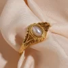 Vintage gold ring with oval pearl design, detailed golden accents.