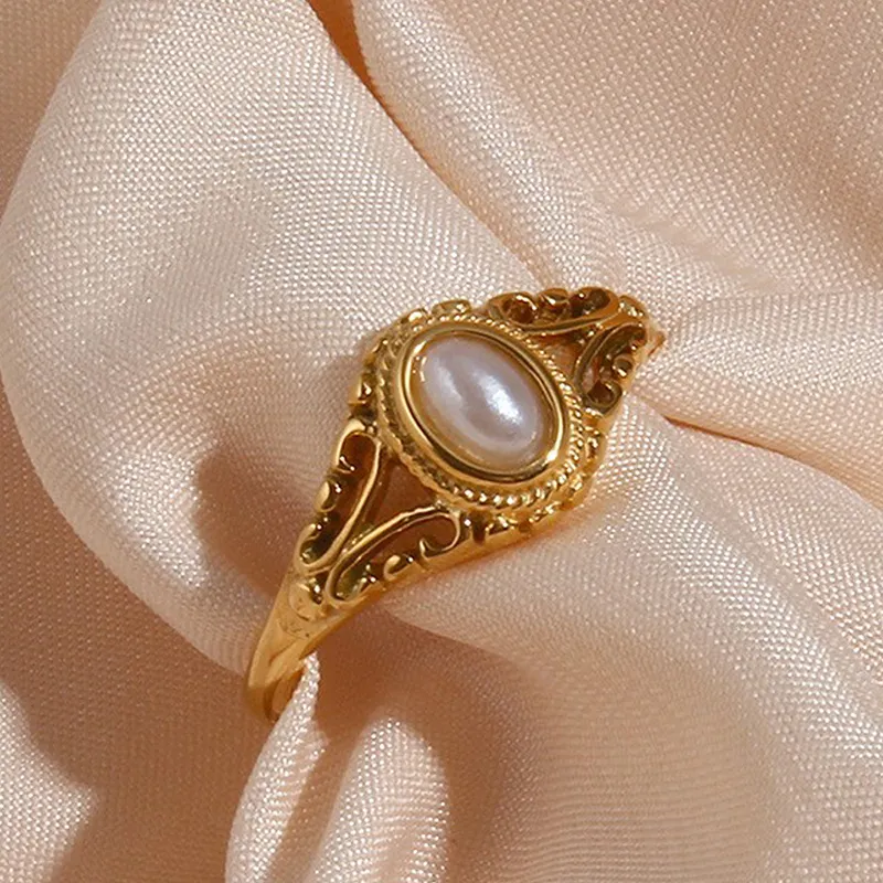 Vintage gold ring with oval pearl design, detailed golden accents.