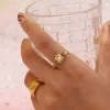 Gold vintage ring with pearl accent, worn on hand holding a clear glass.
