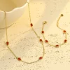 Gold necklace and bracelet set featuring rectangular red cubic zirconia stones, placed elegantly in a gold chain design.