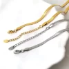 A gold and silver herringbone chain bracelet set with adjustable extenders and lobster clasps, elegantly displayed on a white ceramic dish.