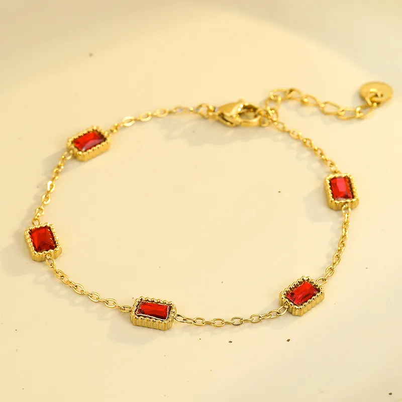Gold bracelet with five rectangular red cubic zirconia stones set in a gold bezel, featuring a chain link design with a clasp closure.