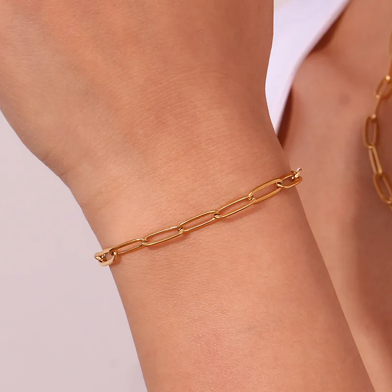 A close-up of a gold paperclip chain bracelet on a woman's wrist, highlighting its delicate and modern design.