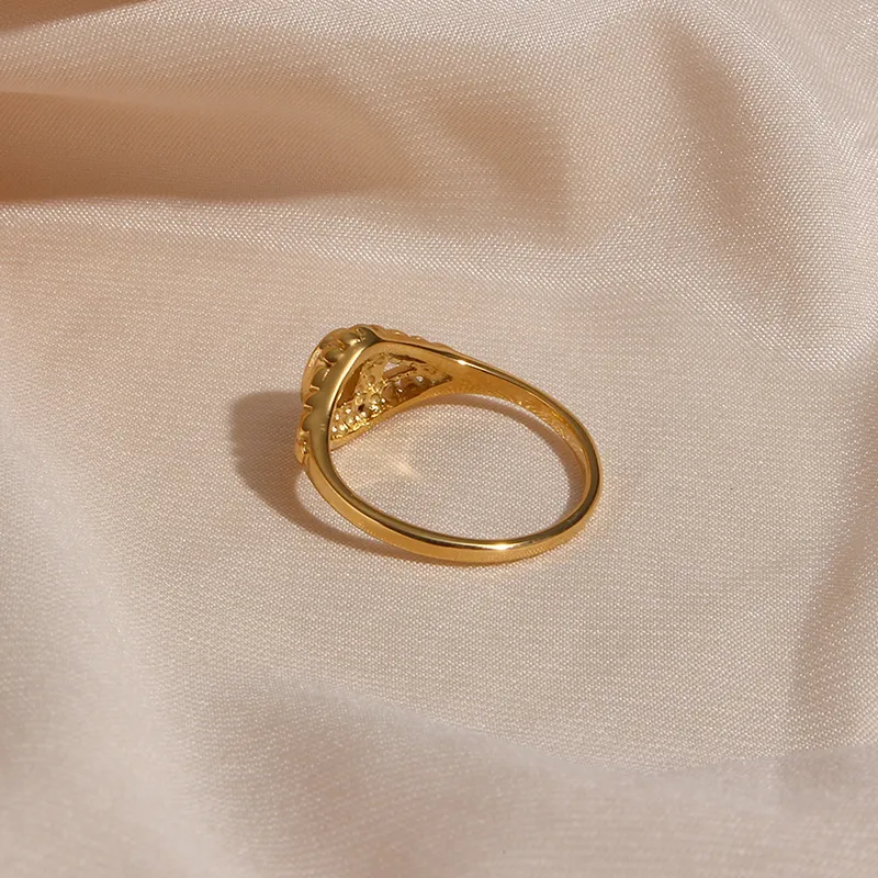 Gold ring with detailed filigree design and pearl accent, viewed from the back.