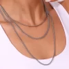 A model wearing a layered silver herringbone chain set, draping elegantly over her collarbone, styled with a white outfit.