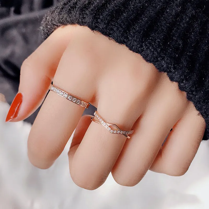 Two rose gold diamond rings worn on a hand with a black sweater, highlighting their polished design and sparkling diamonds.