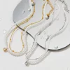 18K gold and silver-plated pearl necklaces with crystal pendants, displayed on a reflective surface with water droplets for an elegant and chic aesthetic.
