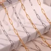 A collection of gold and silver paperclip chain necklaces displayed on a soft, neutral-toned surface, showcasing their sleek and minimal design.