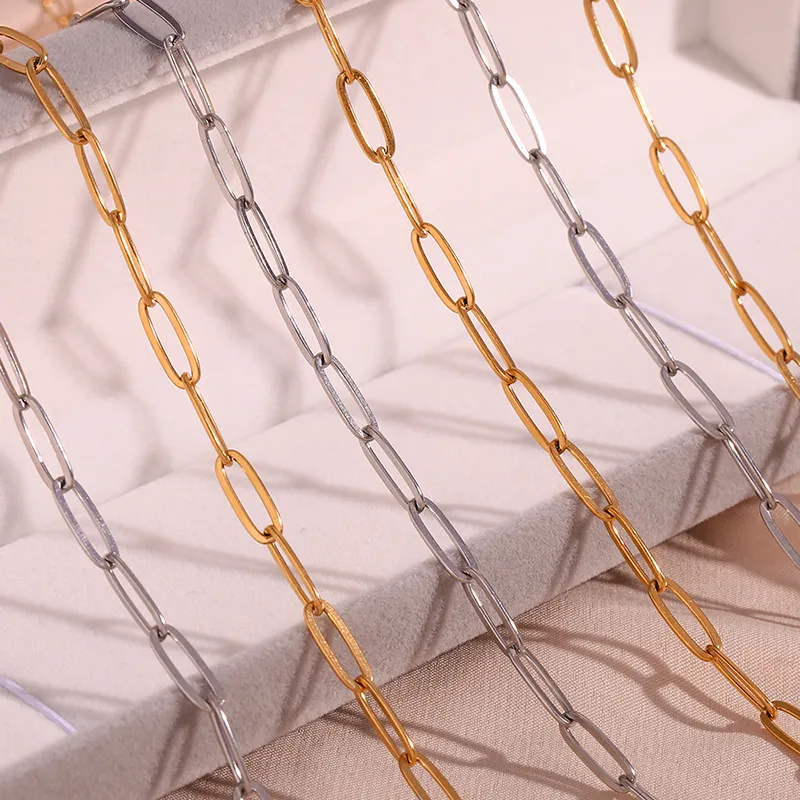 A collection of gold and silver paperclip chain necklaces displayed on a soft, neutral-toned surface, showcasing their sleek and minimal design.