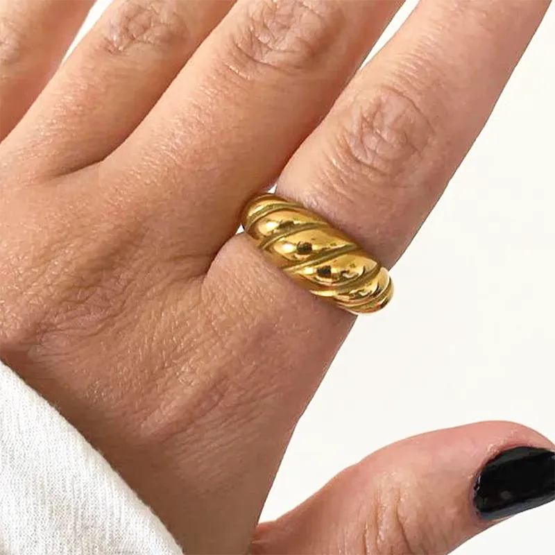 Gold chunky twist ring worn on a hand with black nails, emphasizing its bold design and smooth finish.