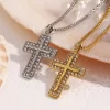 Gold and silver cross necklaces with cubic zirconia crystals, lying on a pearl shell with droplets of water.