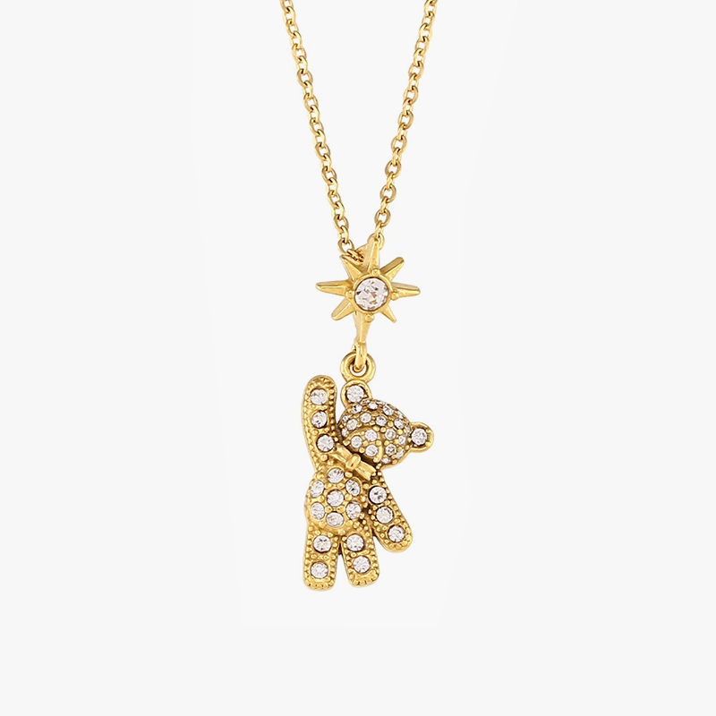 Gold teddy bear pendant with cubic zirconia stones and a star charm on a gold chain, displayed against a white background.