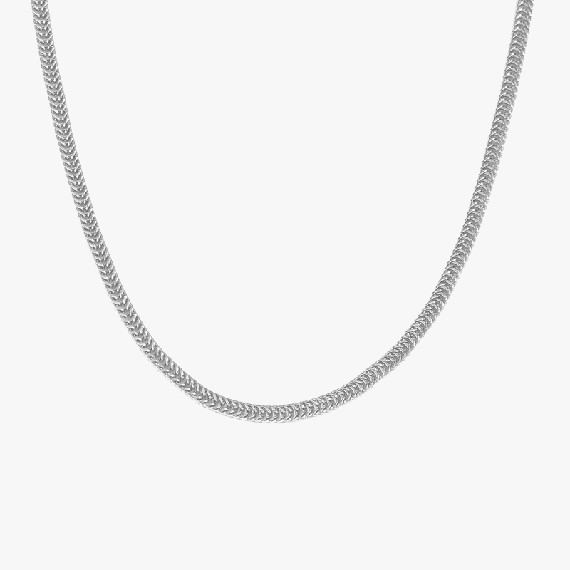 A close-up of a silver herringbone chain against a white background, showcasing its smooth, reflective surface and elegant design.
