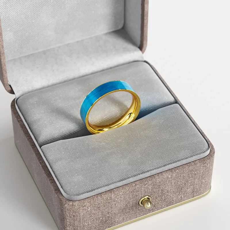 A gold-plated ring with a blue marbled enamel inlay, elegantly displayed in a gray velvet jewelry box, highlighting its modern and sophisticated design.