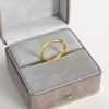 A simple 18K gold-plated band ring, elegantly displayed in a gray velvet jewelry box, emphasizing its minimalist and timeless design.