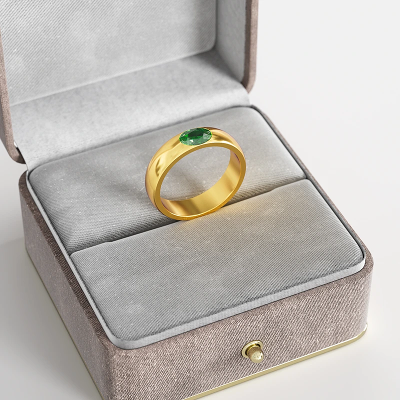 A 18K gold ring with a green cubic zirconia stone, elegantly displayed in a gray velvet jewelry box, emphasizing its modern and bold design.