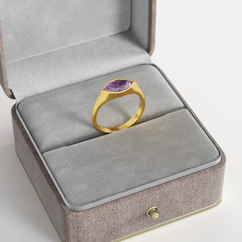 An 18K gold-plated ring with a marquise-cut purple cubic zirconia gemstone, displayed in a gray velvet jewelry box for an elegant presentation.