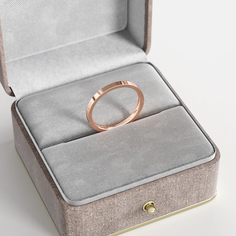 A rose gold flat-edge band ring, displayed in a gray velvet jewelry box, highlighting its minimalist and modern design.