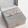 A thin rose gold ring with 10 cubic zirconia stones, elegantly displayed in a gray velvet jewelry box, highlighting its minimalist and sophisticated design.