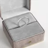 A thin stainless steel ring with 10 cubic zirconia stones, displayed in a gray velvet jewelry box, showcasing its minimalist and elegant design.