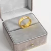 A 18K gold ring with a clear cubic zirconia stone, elegantly displayed in a gray velvet jewelry box, emphasizing its modern and bold design.