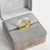 A gold-plated ring with a white marbled enamel inlay, elegantly presented in a gray velvet jewelry box, showcasing its sophisticated and minimalist design.