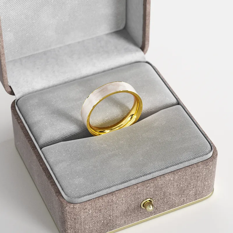 A gold-plated ring with a white marbled enamel inlay, elegantly presented in a gray velvet jewelry box, showcasing its sophisticated and minimalist design.