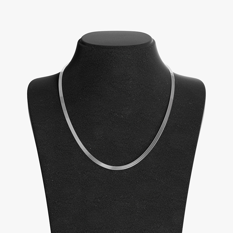 Stainless steel herringbone chain necklace with a smooth, flat design, displayed on a black velvet bust for a sleek and modern look.